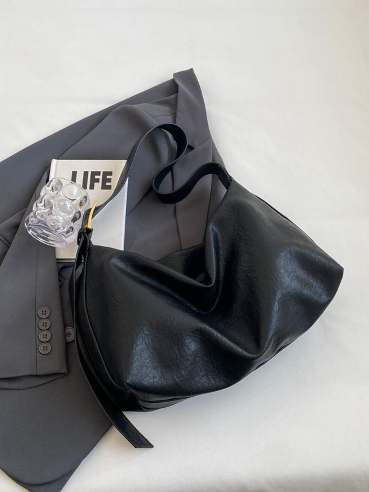 Black leather shoulder bag with adjustable strap and gold hardware detail