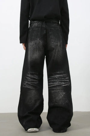 Faded black palazzo jeans with distressed denim and wide legs.