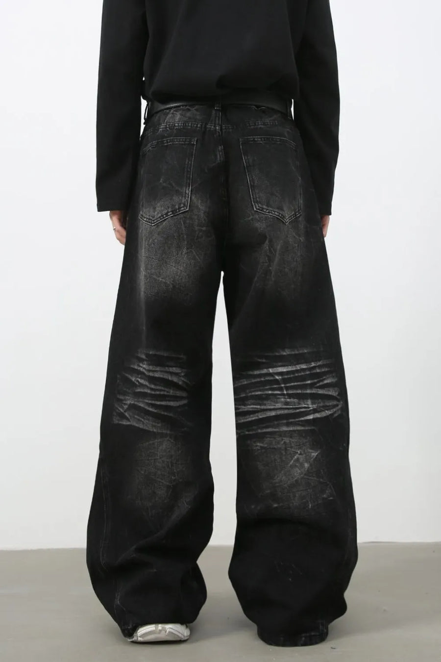 Faded black palazzo jeans with distressed denim and wide legs.