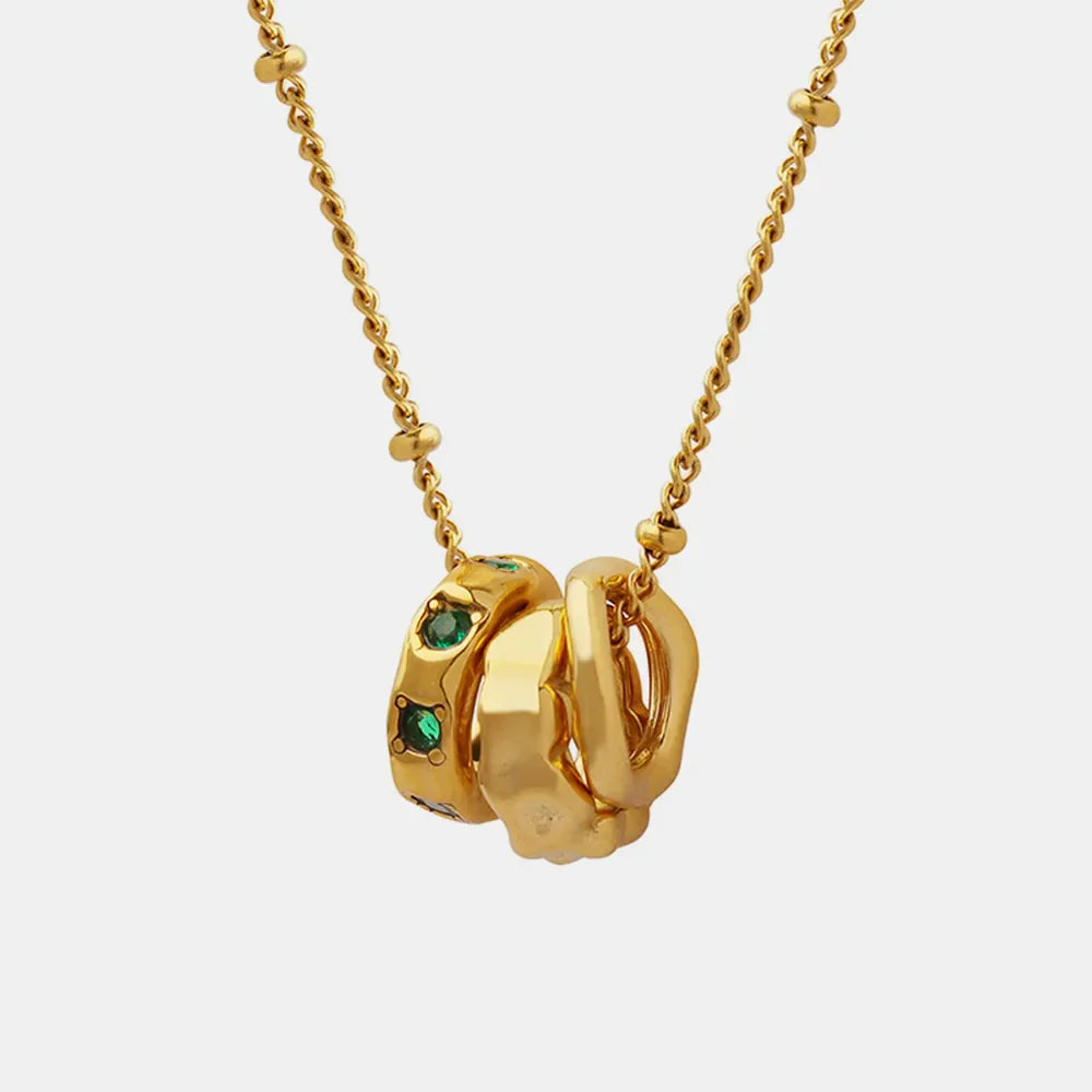 Gold necklace with interlocking circles, one encrusted with emerald green stones.