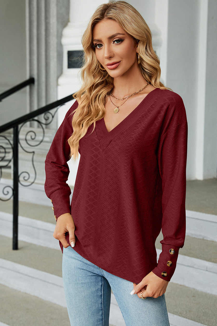 Burgundy diamond-textured V-neck blouse with button cuffs and long sleeves.