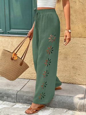 Green wide-leg linen pants with floral cut-outs and drawstring waist.