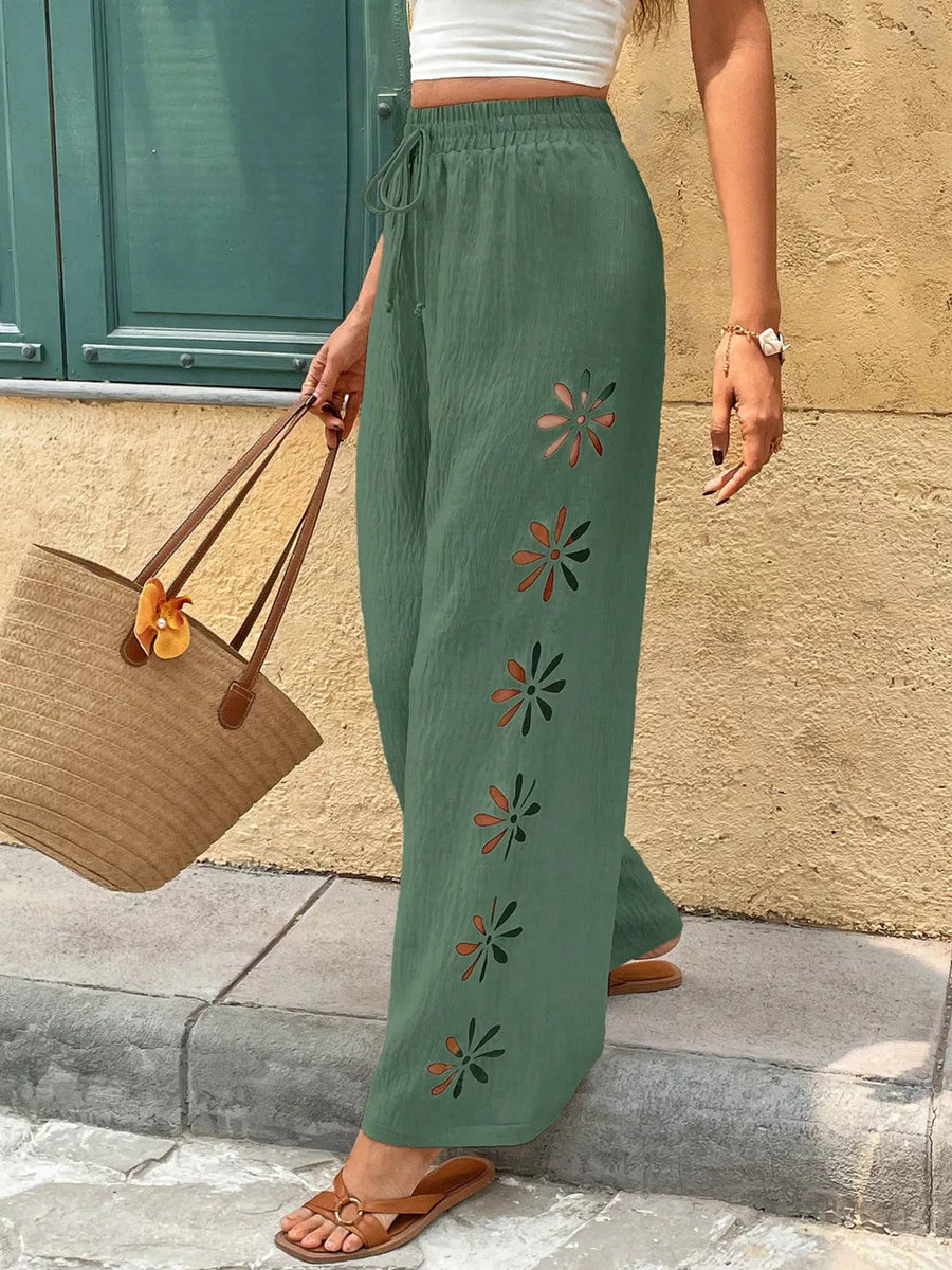 Green wide-leg linen pants with floral cut-outs and drawstring waist.