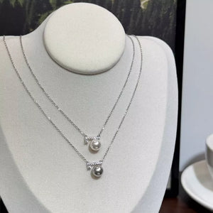 Lustrous pearl pendant necklaces with zircon accents, one light gray pearl, one cream pearl.