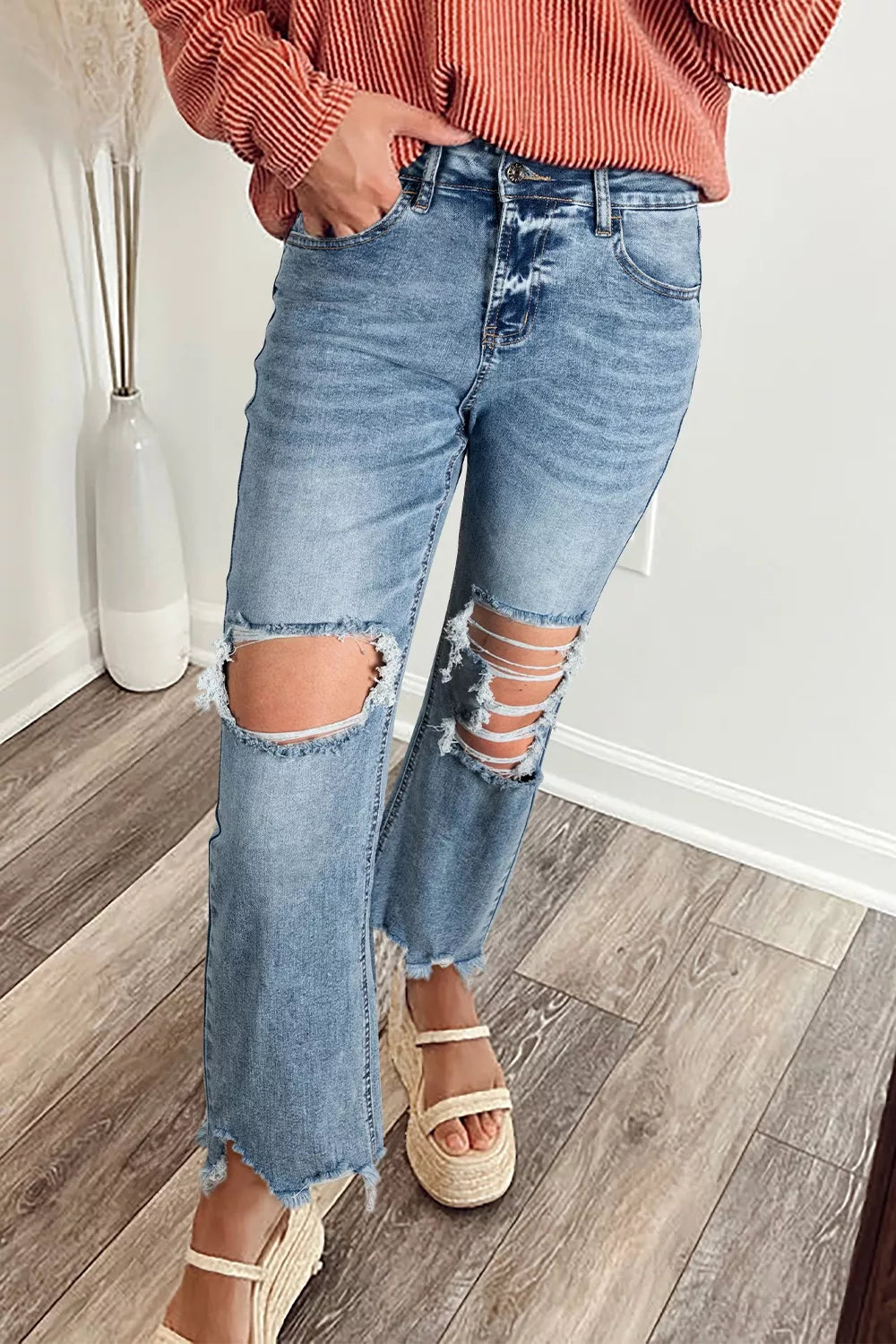 Distressed open knee flare jeans in light wash denim with frayed hem and ankles.