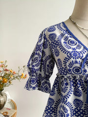 Chic floral tie-front blouse with 3/4 ruffled sleeves and blue floral print on white.