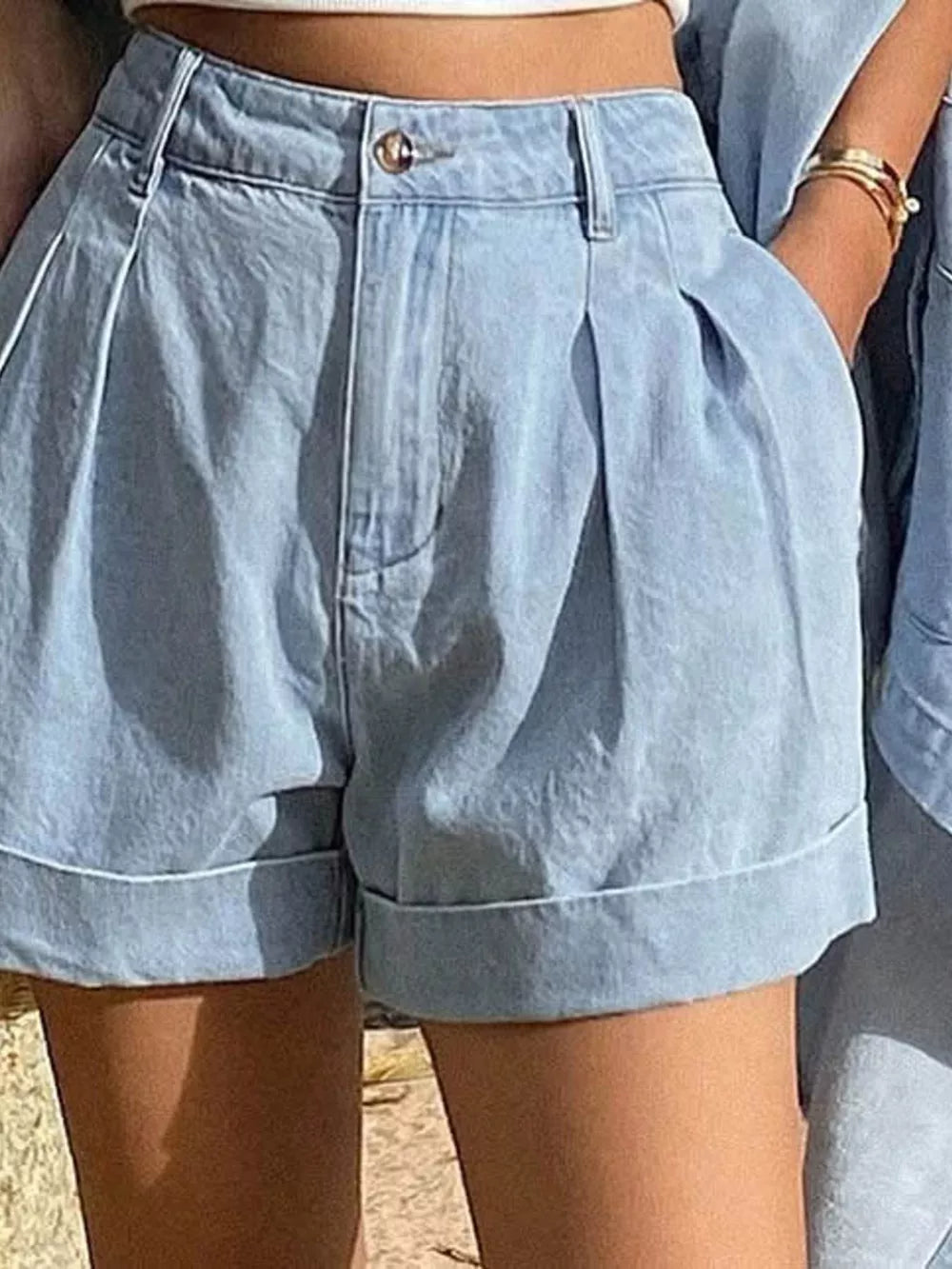 Light blue denim shorts with pleats and cuffed hems, part of a button-up shirt and shorts set.
