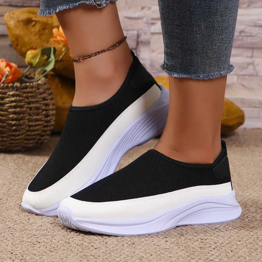 Black mesh slip-on sneakers with white stripe detail and white sole.