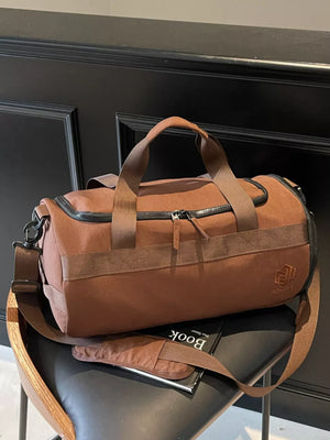 Brown Oxford cloth duffel bag with carry handles and adjustable strap.