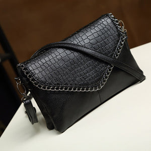 crossbody bag in black with crocodile-print and chain strap detail