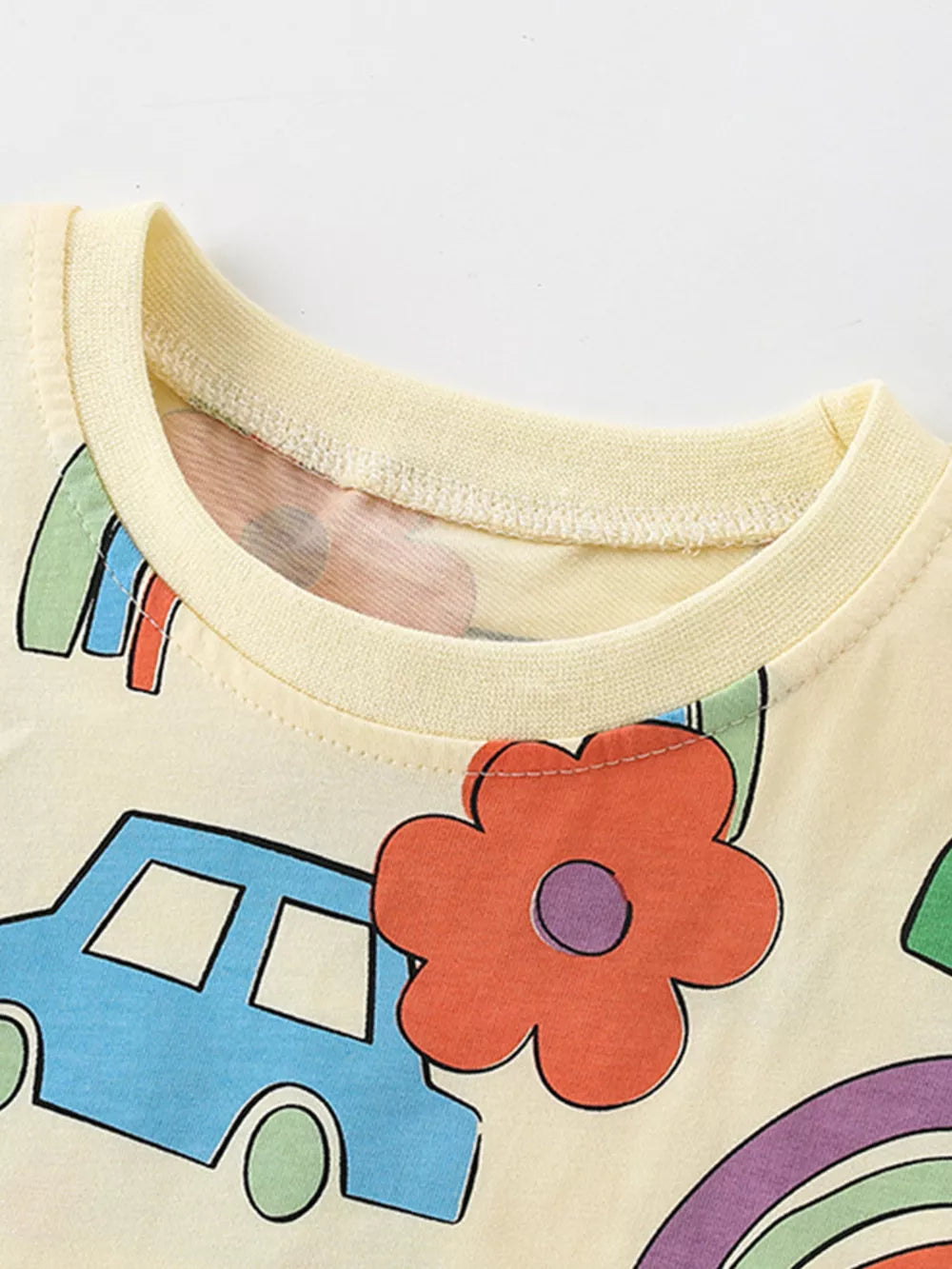 Baby T-shirt in cream cotton with playful cartoon car, rainbow, and flower print.