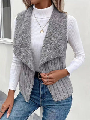 Gray fleece vest with open front and ribbed knit body, styled with a white turtleneck and jeans.