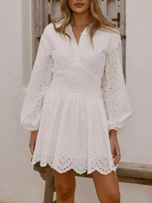 White eyelet mini dress with balloon sleeves, smocked waist, and scalloped hem.