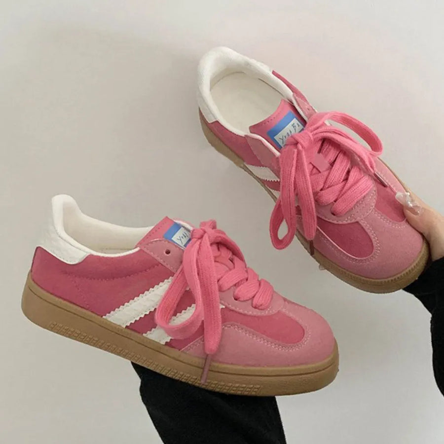 Pink suede sneakers with white signature stripes and gum sole.
