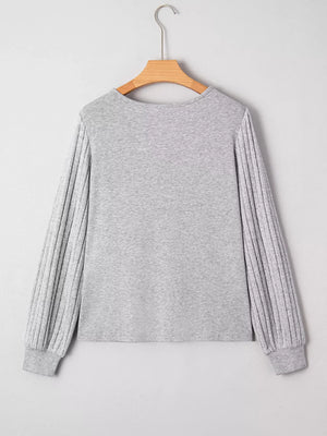 Gray ribbed knit long-sleeve top with textured sleeves and crew neck.