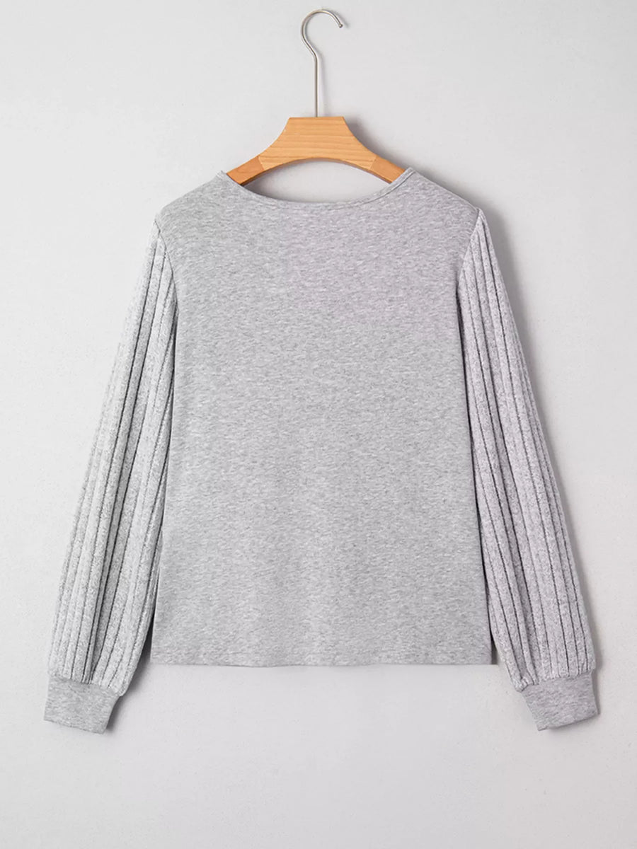 Gray ribbed knit long-sleeve top with textured sleeves and crew neck.