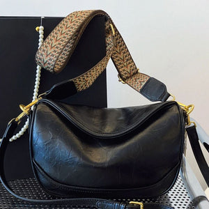 Black vintage wide strap crossbody bag with adjustable patterned strap and gold hardware.