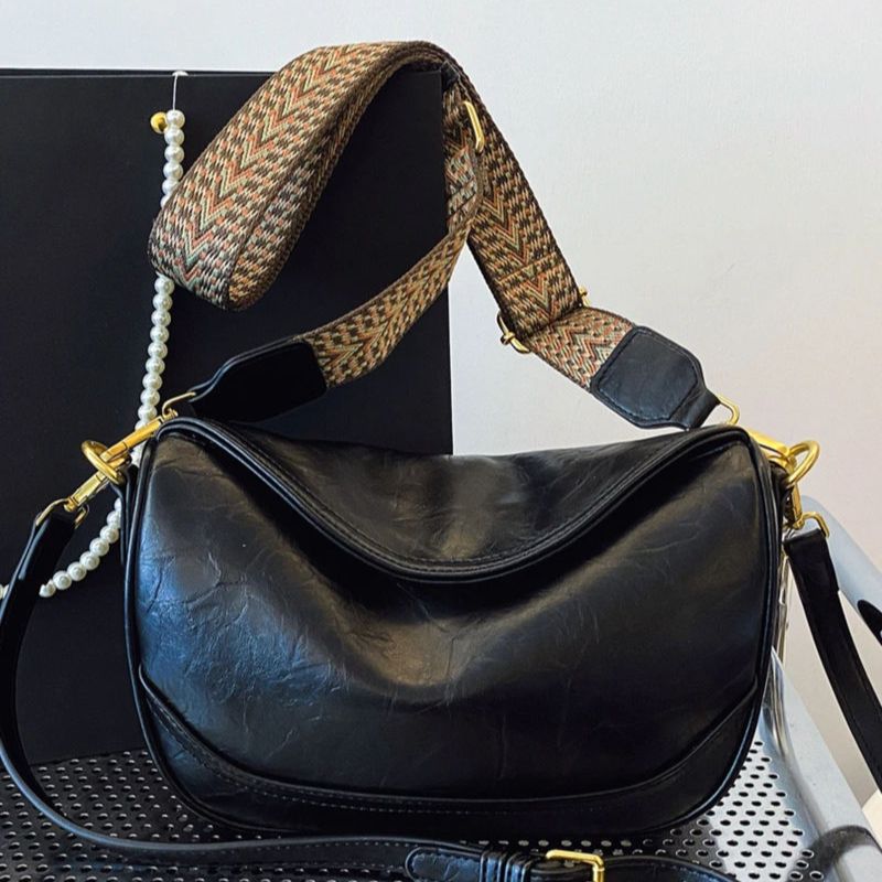 Black vintage wide strap crossbody bag with adjustable patterned strap and gold hardware.
