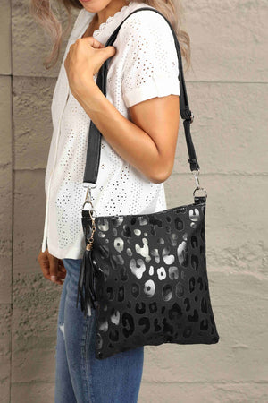Black leopard print embossed crossbody bag with tassel detail.