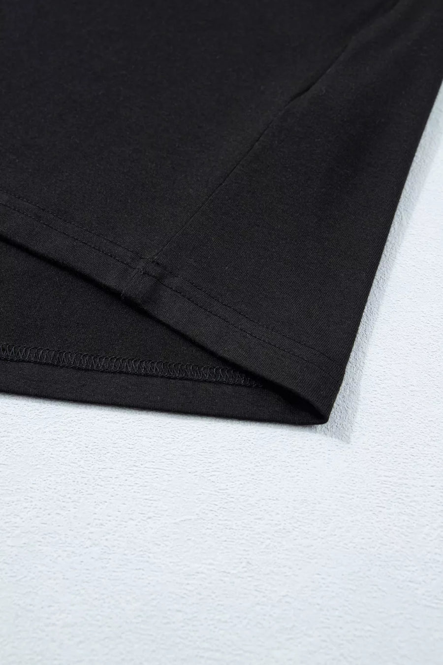 Black tie-wrap two-piece ensemble detail showing hem stitching