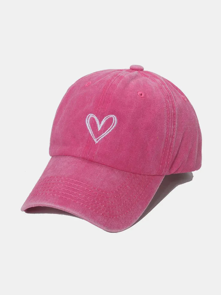 Washed cotton baseball cap in hot pink with white embroidered heart detail.