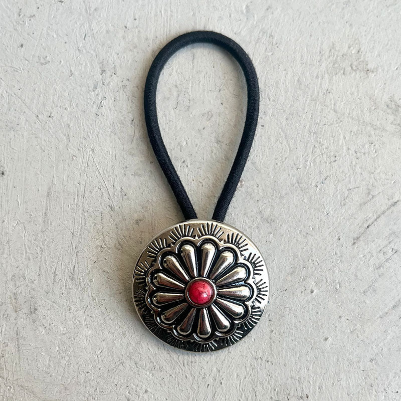 Southwestern hair tie with silver alloy medallion and red stone detail on black elastic band.
