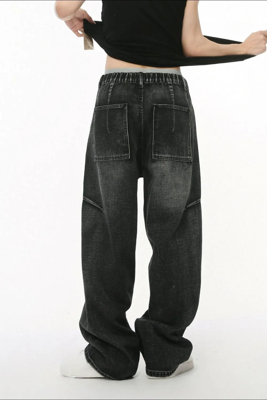 Dark wash denim trousers with exaggerated seam details and large back pockets.