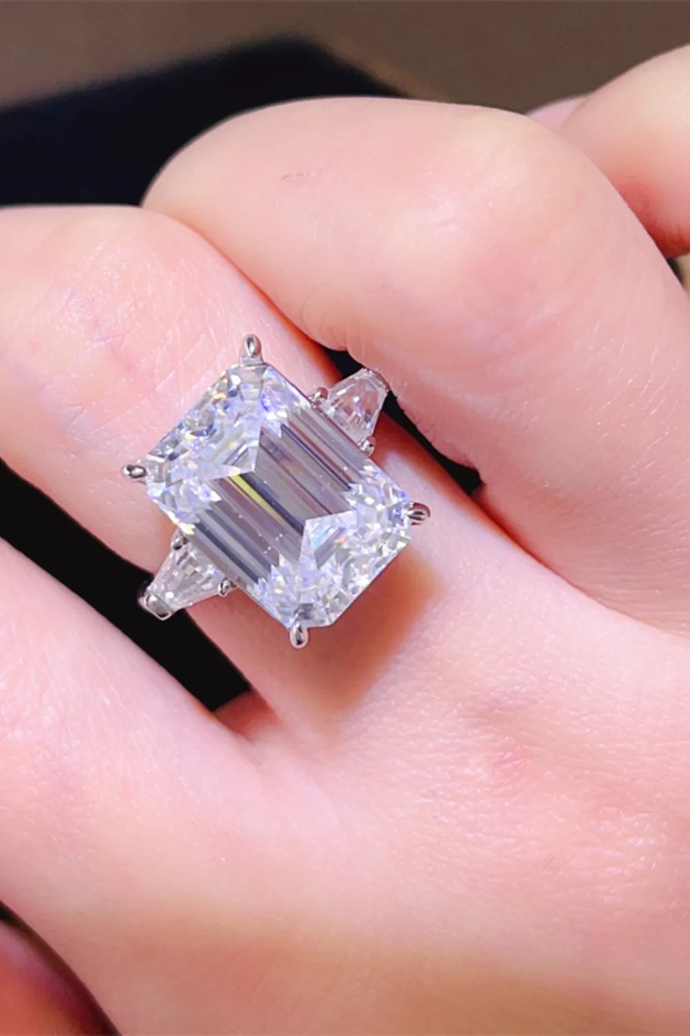 Silver ring with large emerald cut diamond and two side trapezoid diamonds