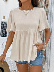 Charming babydoll blouse with pom-pom trim and short sleeves.