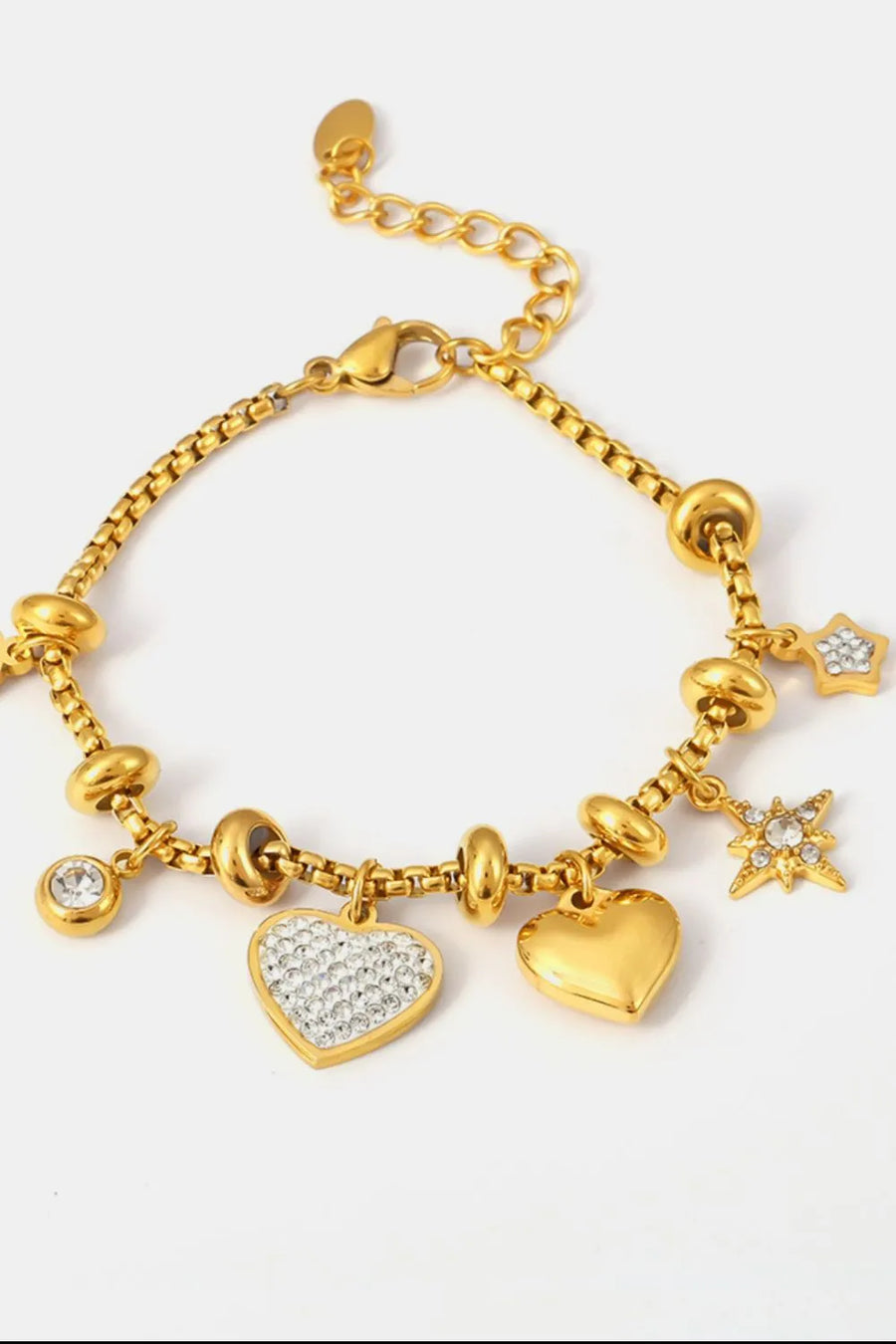 Gold charm bracelet with heart and star charms, featuring cubic zirconia accents.