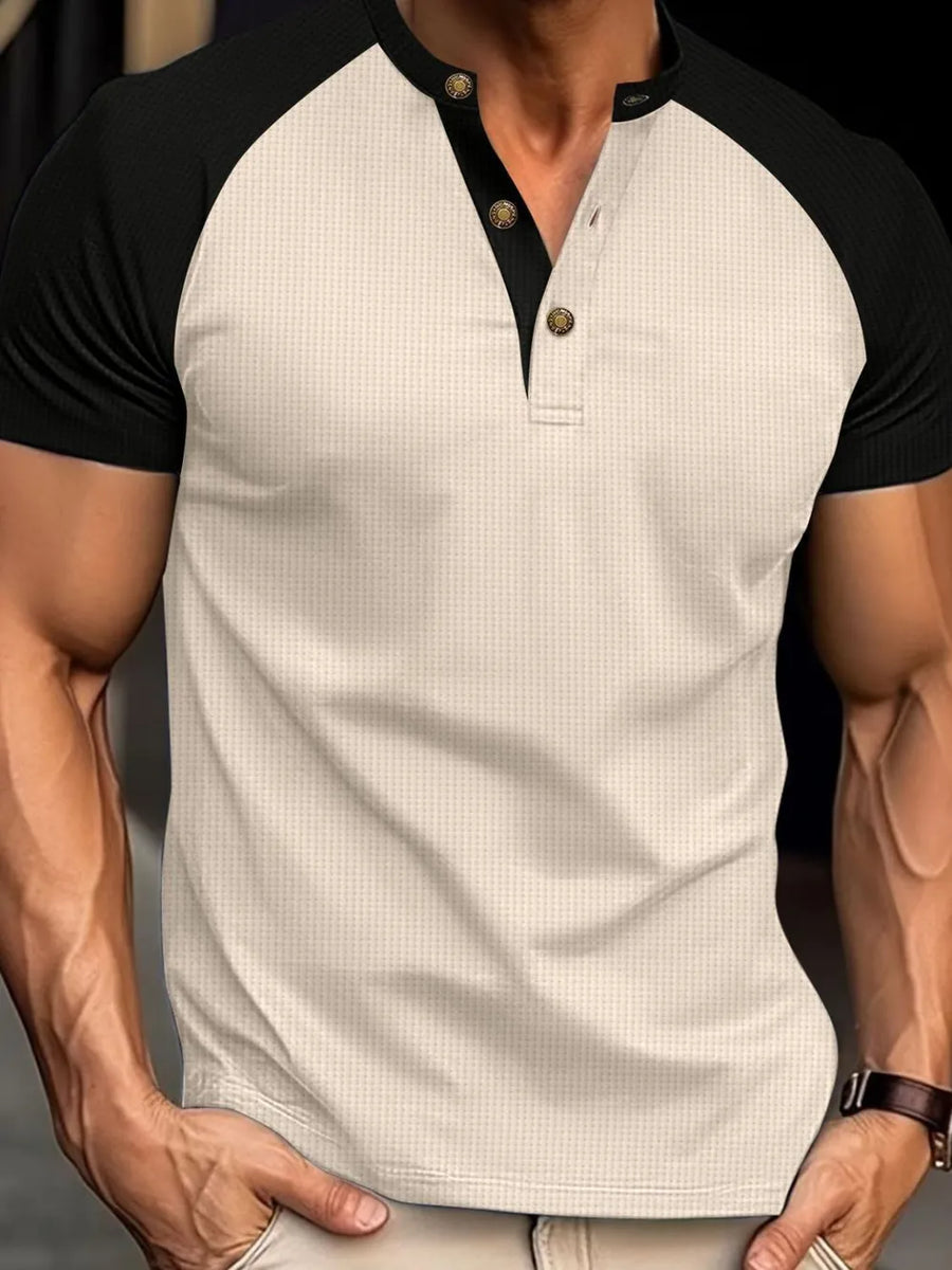 Beige raglan henley polo shirt with black sleeves and textured fabric.