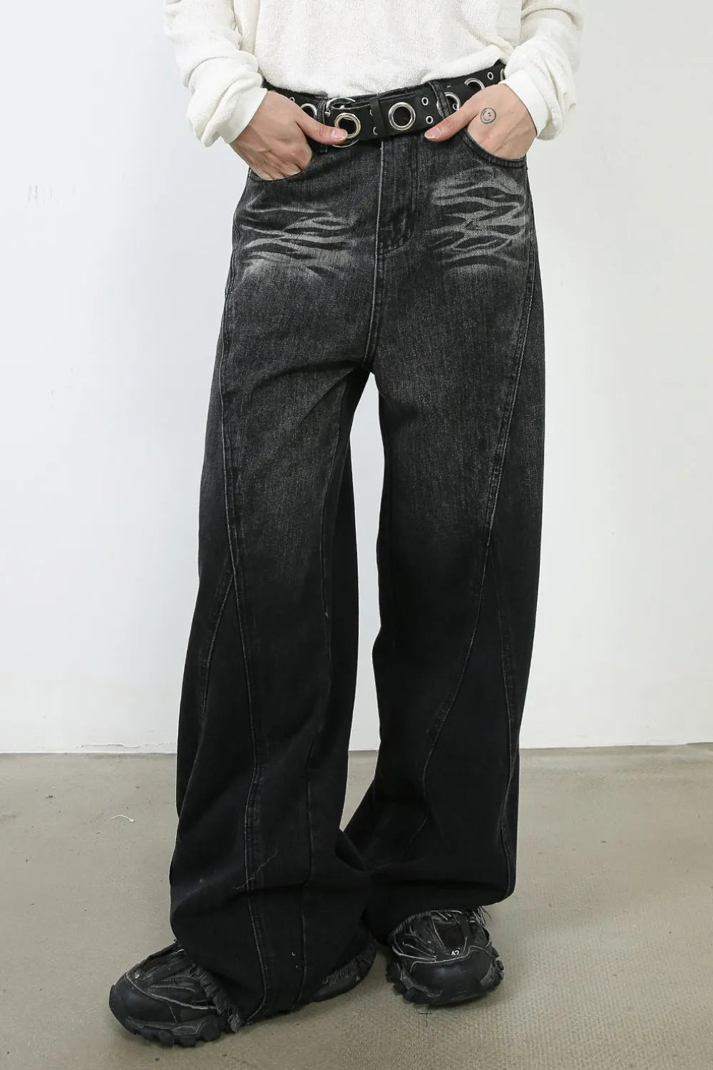 Dark denim palazzo trousers with a wide leg and sculpted seams, styled with a belt.