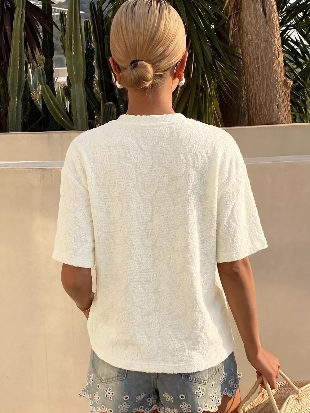 Textured white paisley t-shirt with short sleeves and a crew neck, styled with denim shorts.