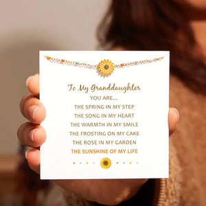 Gold beaded bracelet with sunflower charm and colorful beads, presented on a card.