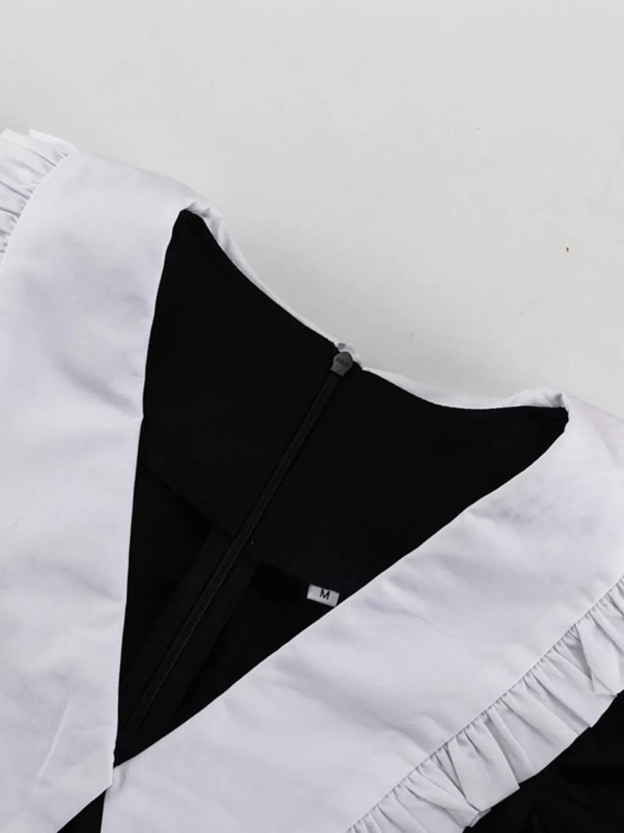 Black dress with white ruffled collar and cuffs, V-neck, zipper closure