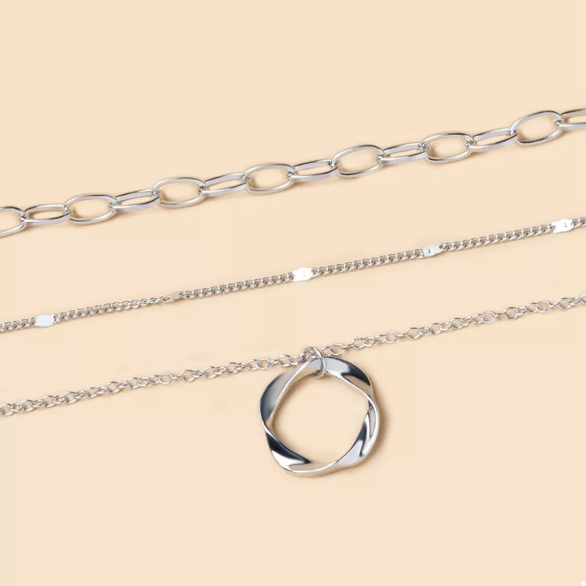 Silver layered necklace with a twisted circle pendant and delicate chains.