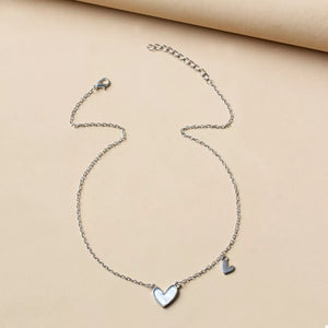 Silver chain necklace with a white heart pendant and a small heart charm.