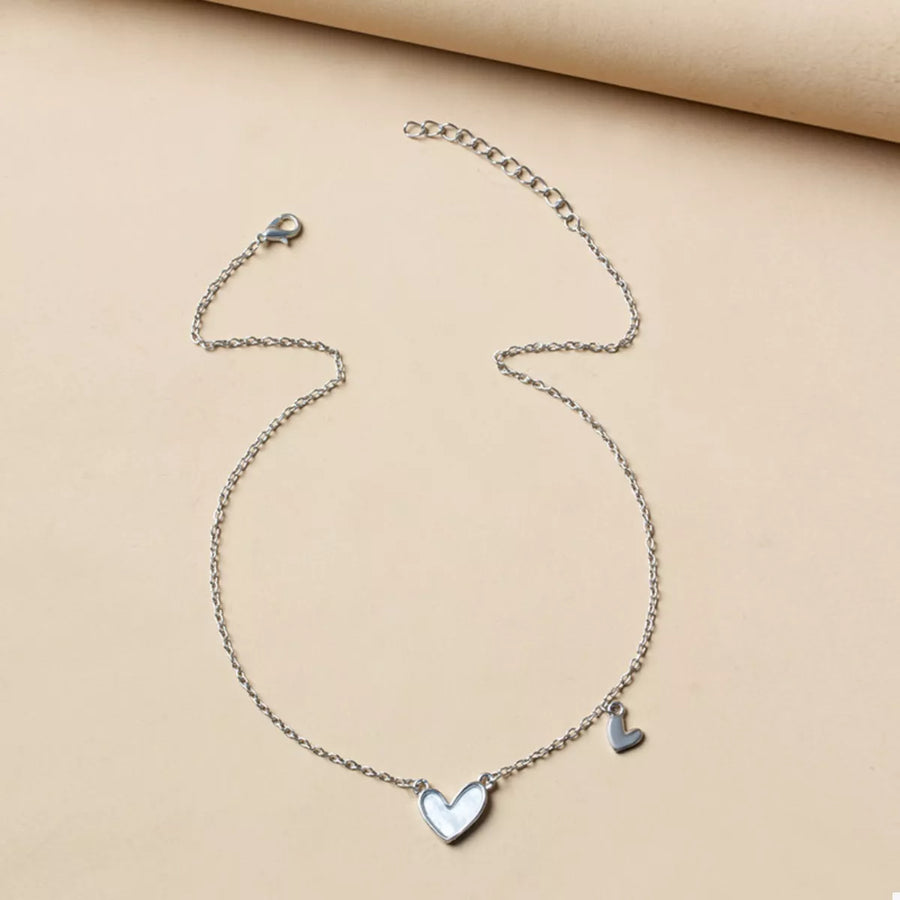 Silver chain necklace with a white heart pendant and a small heart charm.