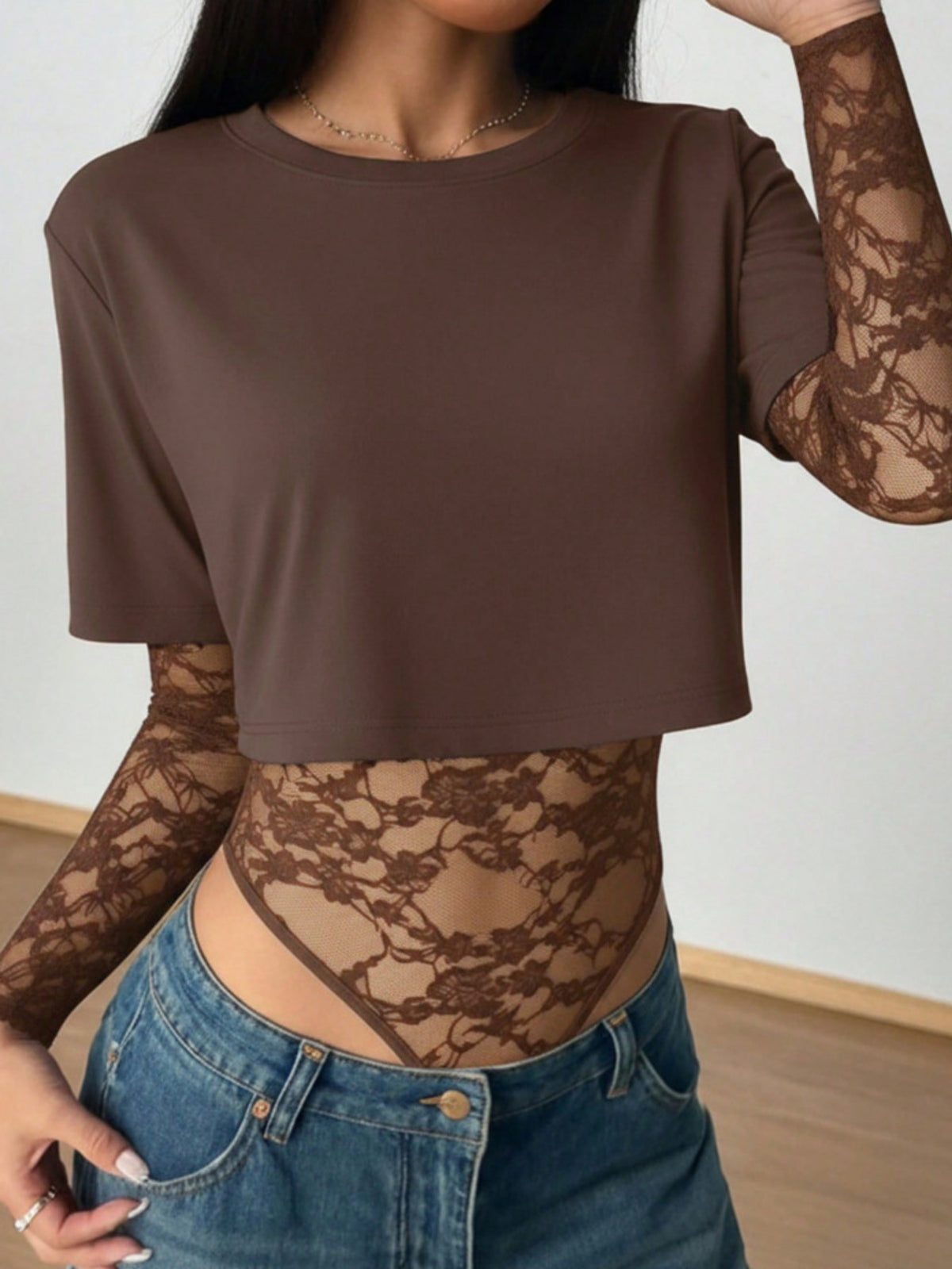 Brown lace patchwork bodysuit with sheer sleeves and a cropped top.