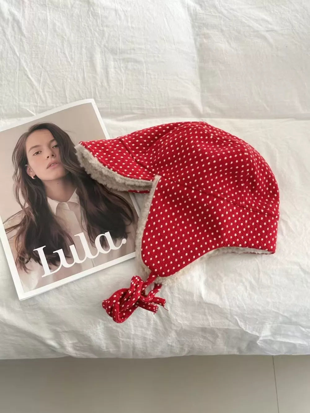 Red polka dot fleece hat with cream lining and ear flaps.