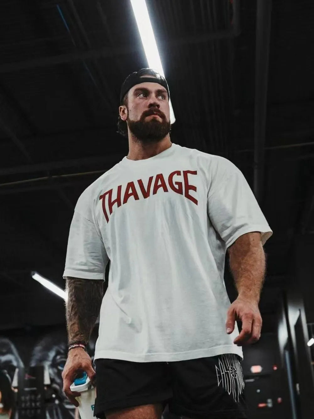 White oversized graphic tee with red THAVAGE print, crew neck, short sleeves.