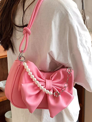 Pink bowknot pearl chain shoulder bag with a crescent shape and chain detail.