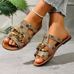 Patterned slide sandals in apricot with gold chain accent and brown trim.