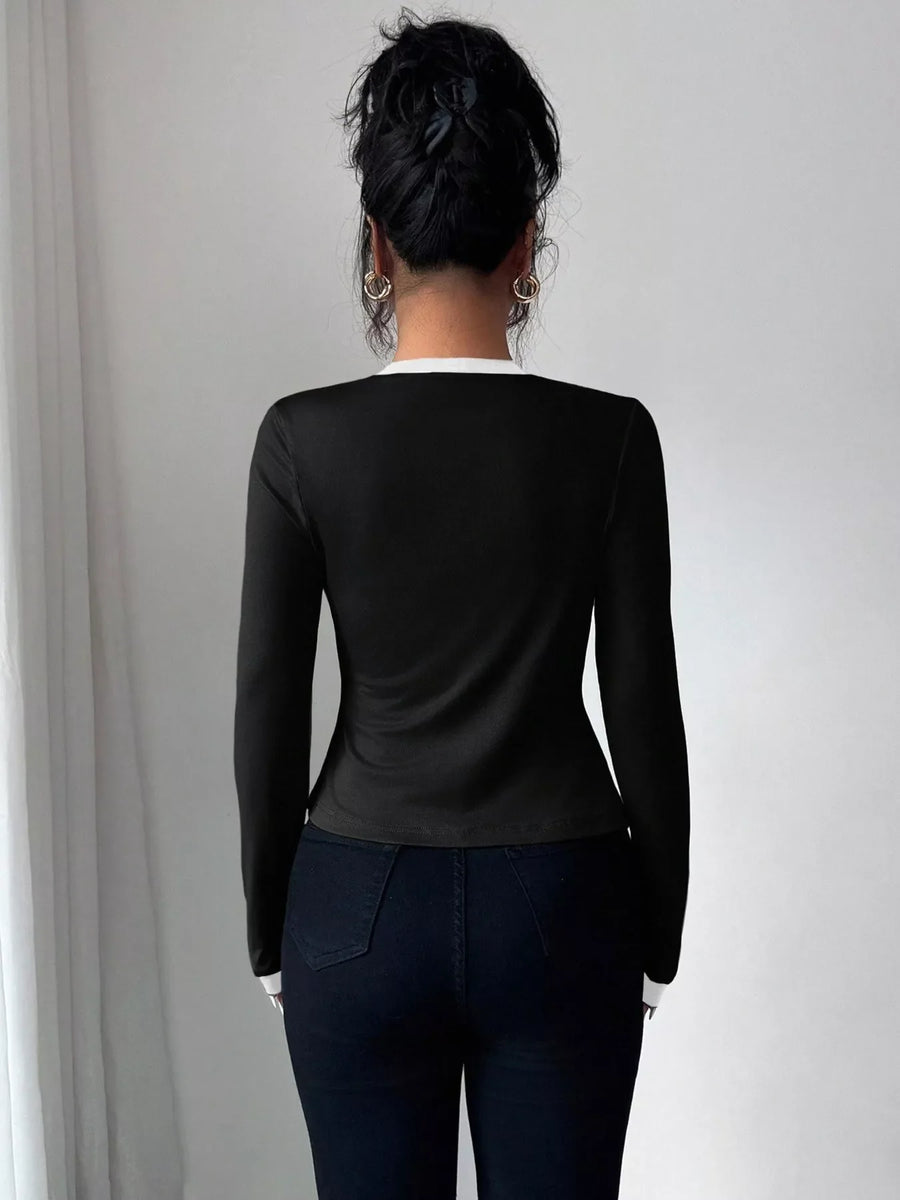 Black long sleeve top with white trim detail, part of a cardigan set.