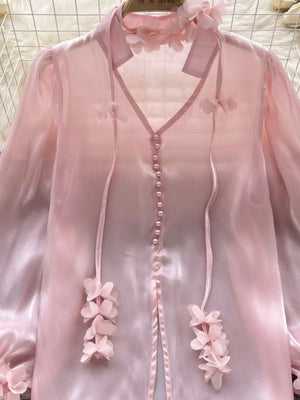 Pink sheer organza shirt with floral appliqué and pearl buttons.