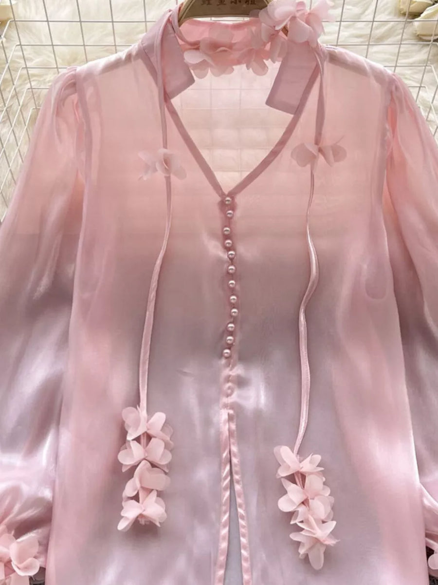 Pink sheer organza shirt with floral appliqué and pearl buttons.