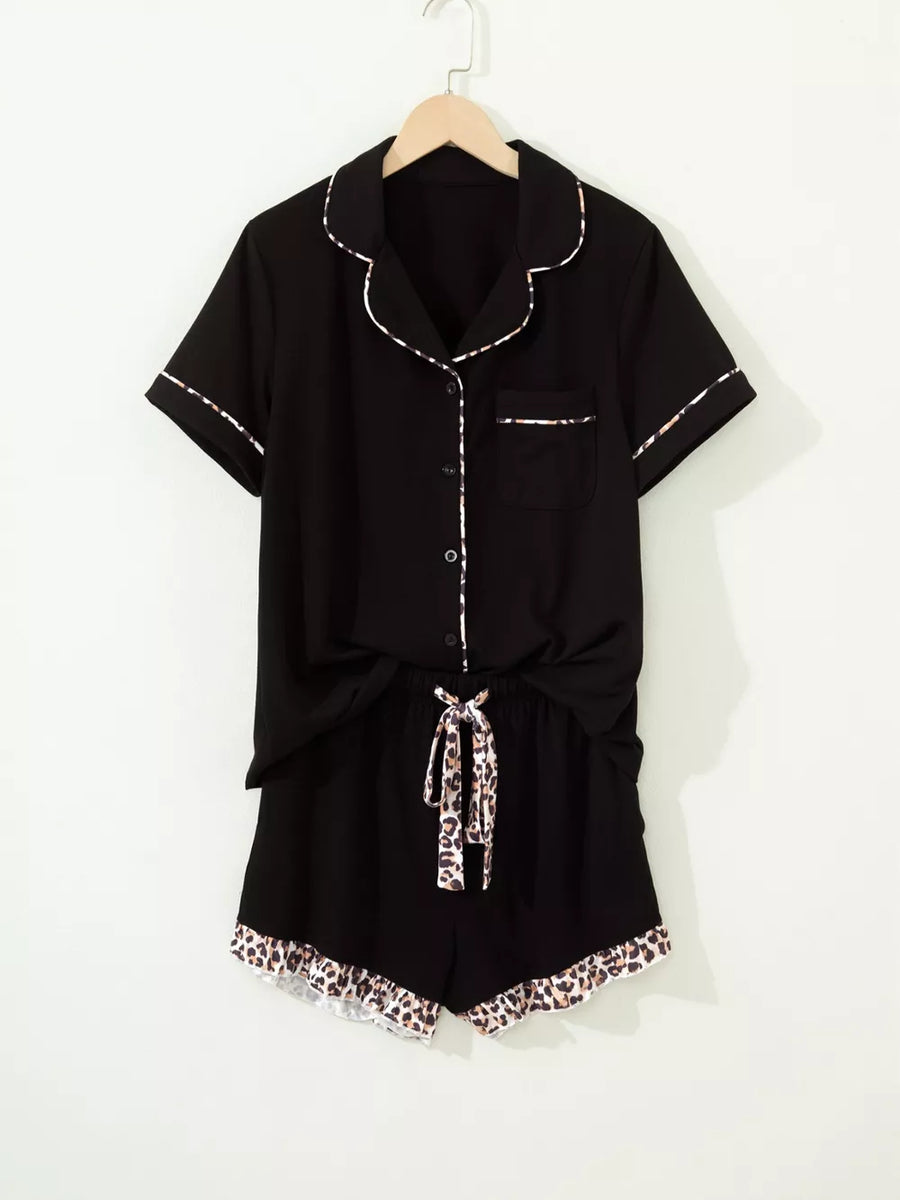 Black button-up pajama set with leopard trim on collar, cuffs, pocket, shorts tie and hem.