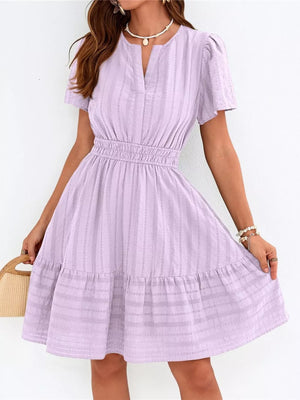 Textured purple V-neck tiered dress with smocked waist and short sleeves.
