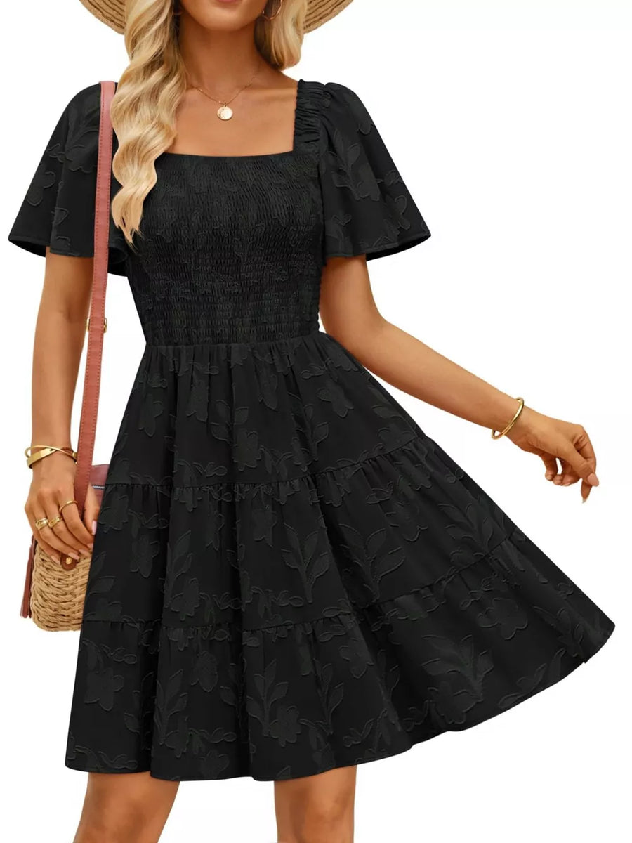 Black smocked mini dress with tiered skirt, square neck, and flutter sleeves.