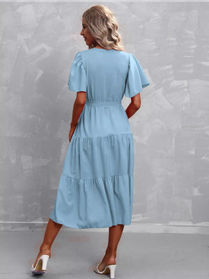 Light blue tiered midi dress with flutter sleeves and belted waist.